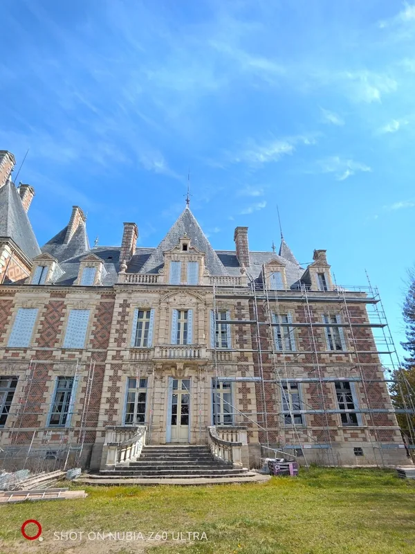 The full brick-and-stone facade beneath dramatic cloud