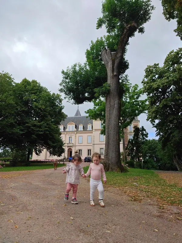 Children running together on the estate drive, the chateau behind them