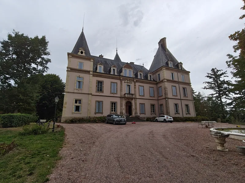 The full front facade of the chateau seen across the gravel drive, with the fountain in the foreground