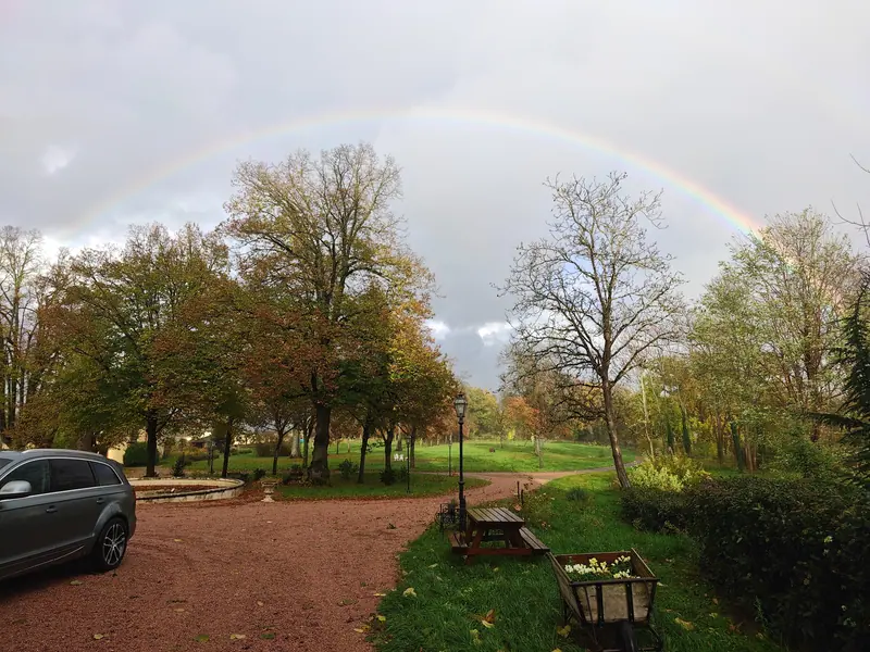 A full rainbow arching over the estate driveway after rain
